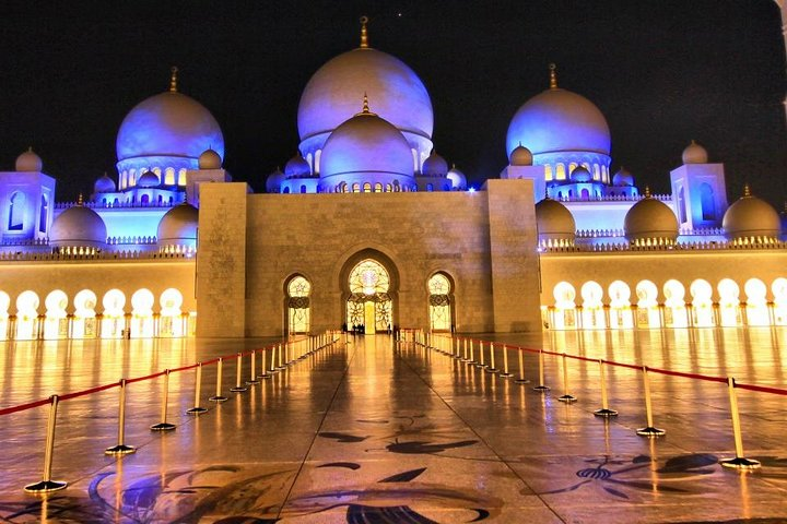 Experience the stunning beauty of Sheikh Zayed Mosque at night where illuminated domes create a magical scene that showcases the grandeur of Abu Dhabi's architectural heritage.